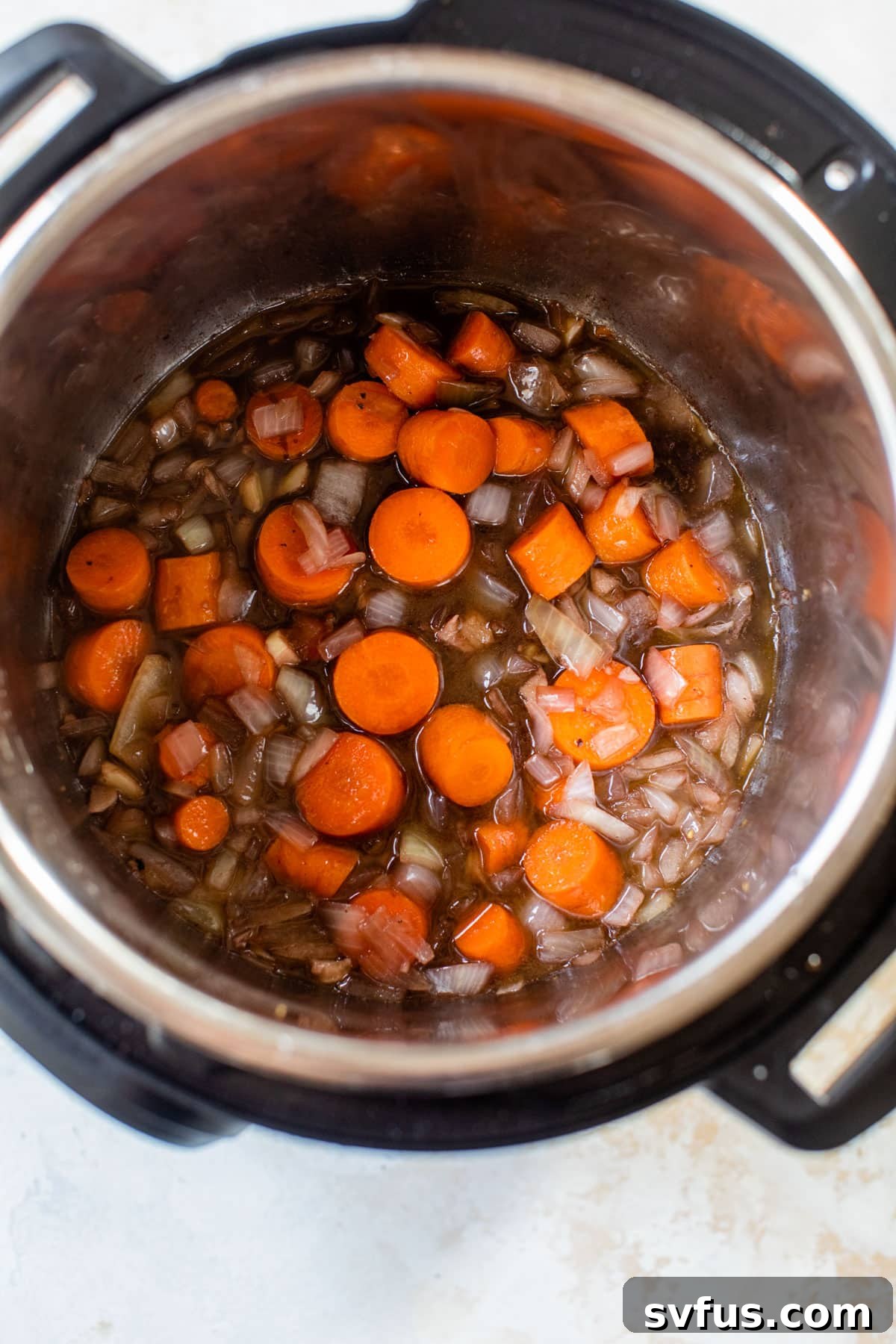 Sautéed carrots and onions in the Instant Pot with red wine just added, beginning the deglazing process.