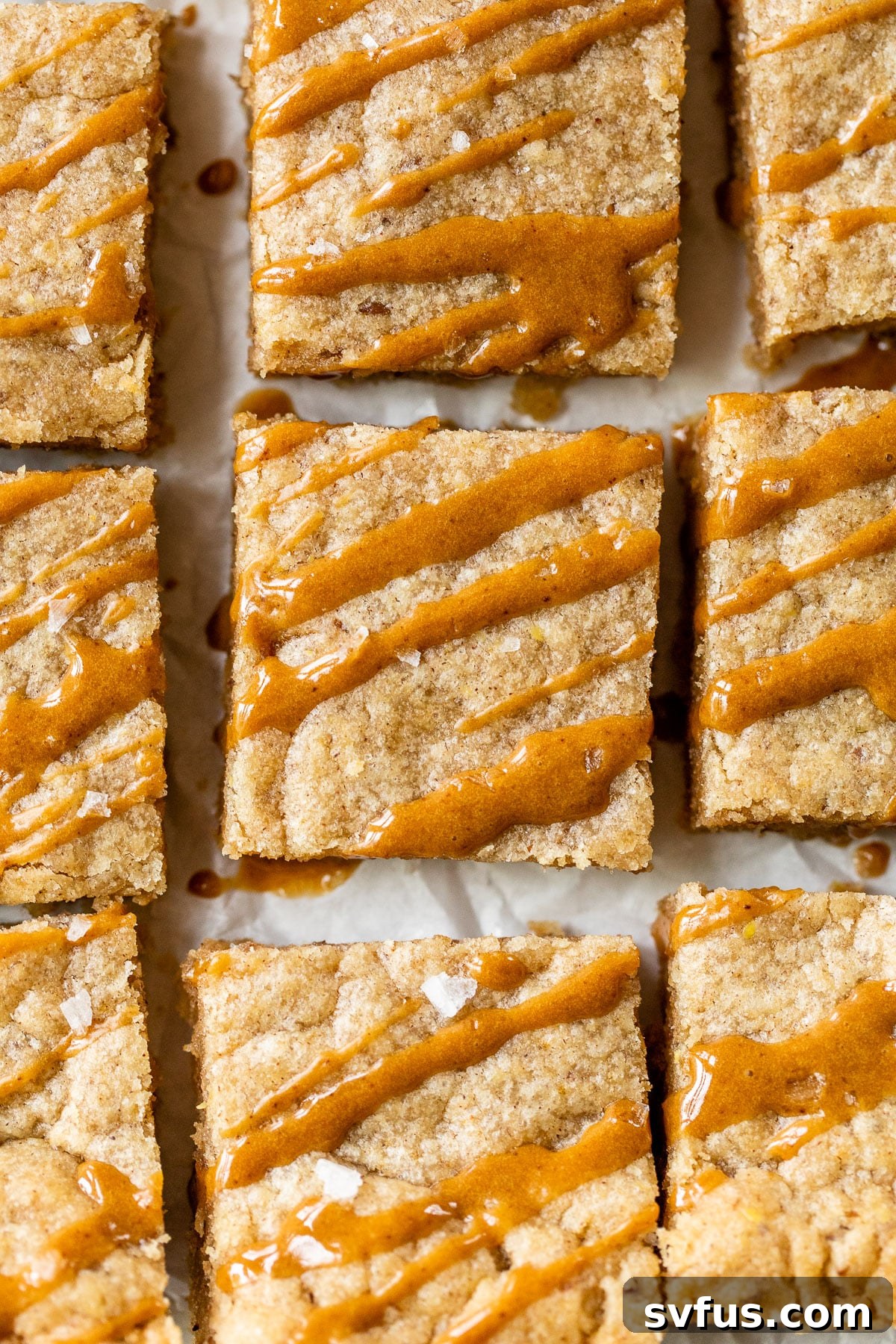 Blondie bars cooling on parchment paper, adorned with a decorative espresso glaze drizzle.