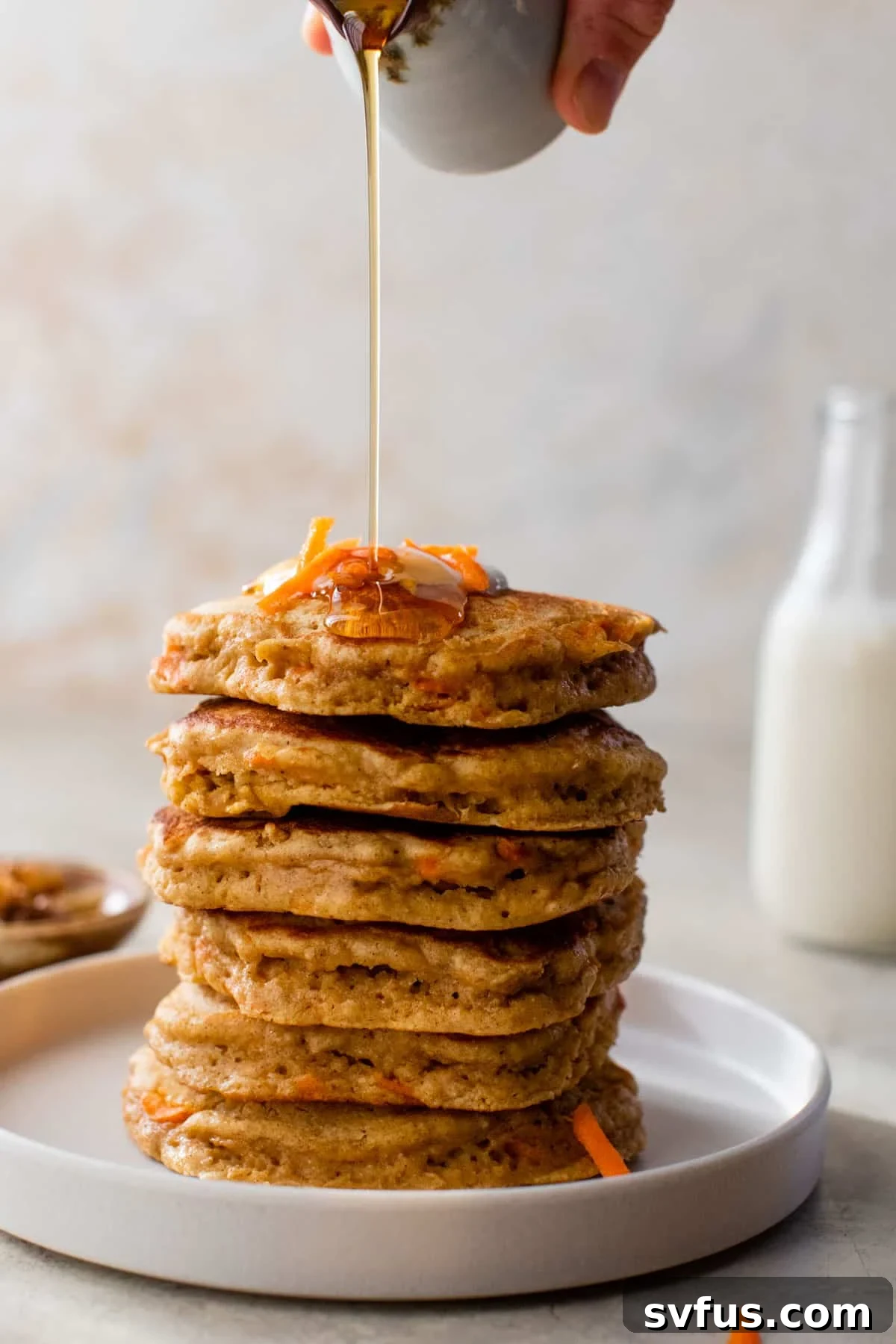 side view of a stack of carrot pancakes with syrup poured on top