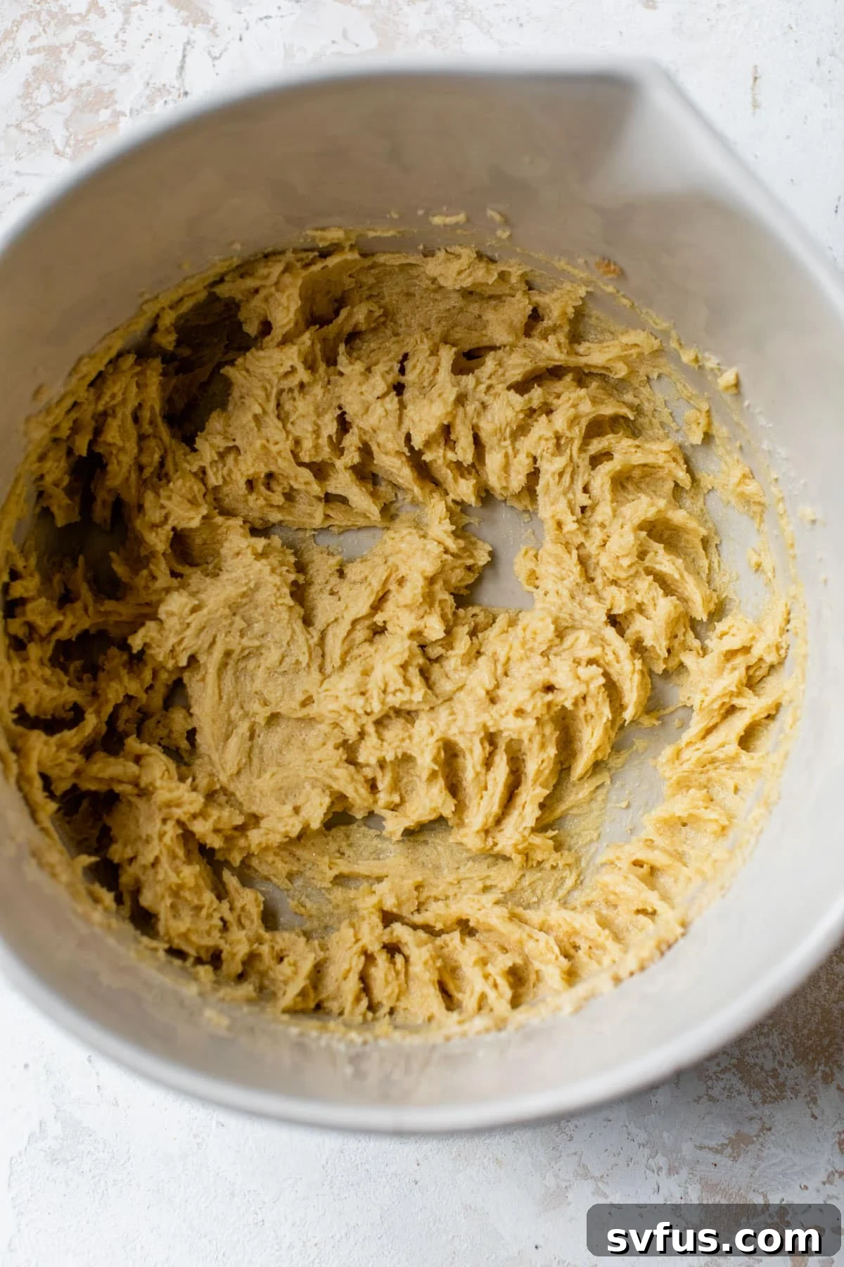A large bowl filled with creamy cookie dough, showing the texture and readiness for baking