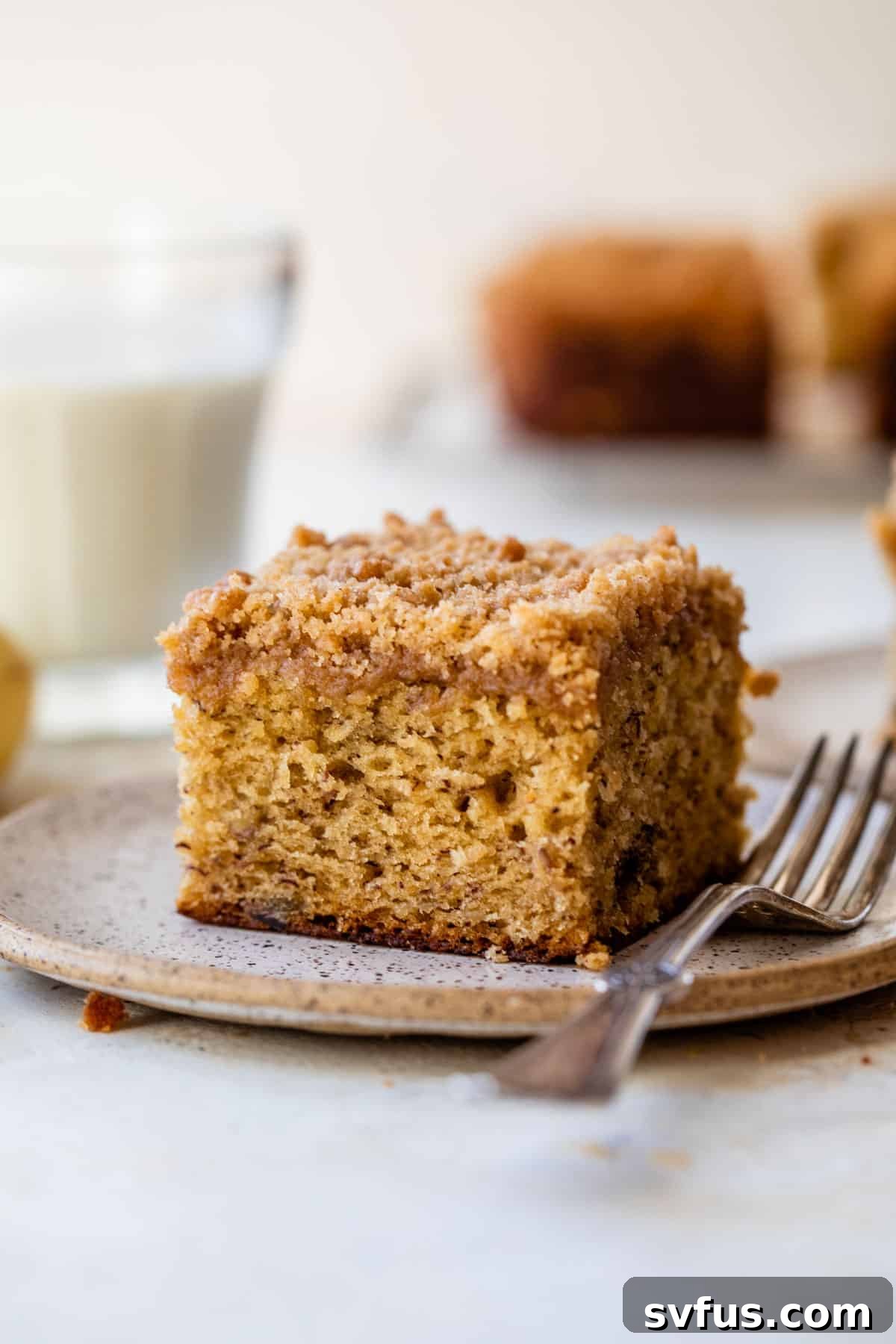 side view of a slice of banana coffee cake on a plate with a fork