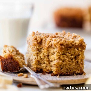 side view of a slice of banana coffee cake with a bite taken out on a plate with a fork