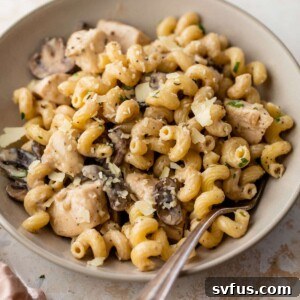 A beautifully plated bowl of creamy chicken mushroom pasta, garnished with fresh parmesan cheese.
