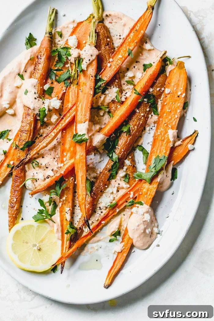 Close-up shot of roasted carrots topped with crumbled feta cheese and a red spice blend, showing their tender texture and vibrant color.