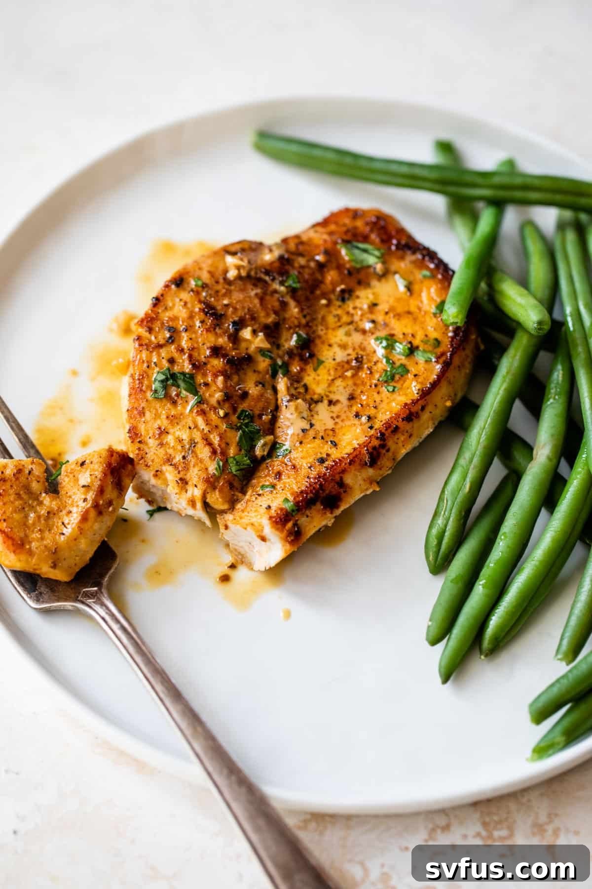 Cajun chicken served on a white plate with a fork and fresh green beans, garnished with herbs.