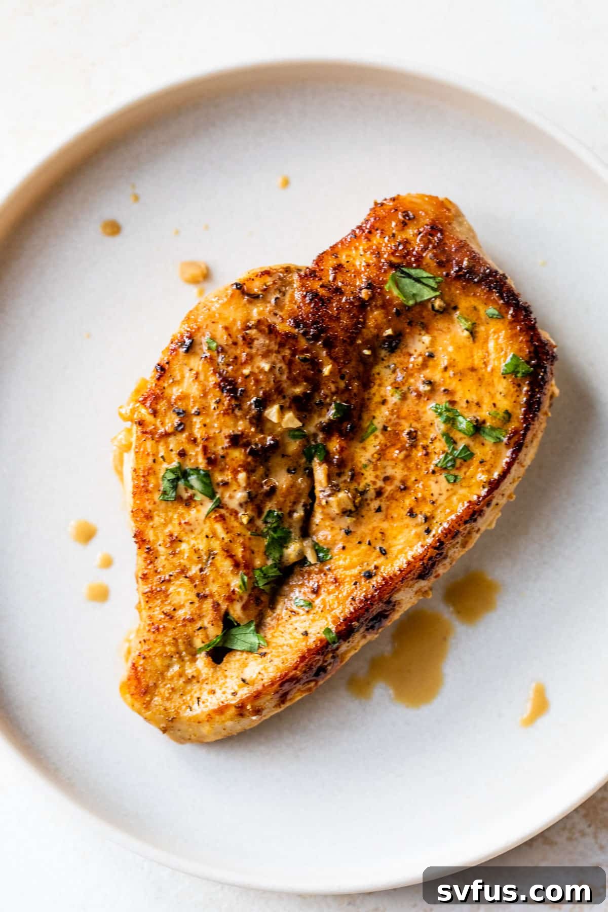 A close-up of a serving of Cajun chicken on a white plate, showcasing its creamy sauce and savory presentation.