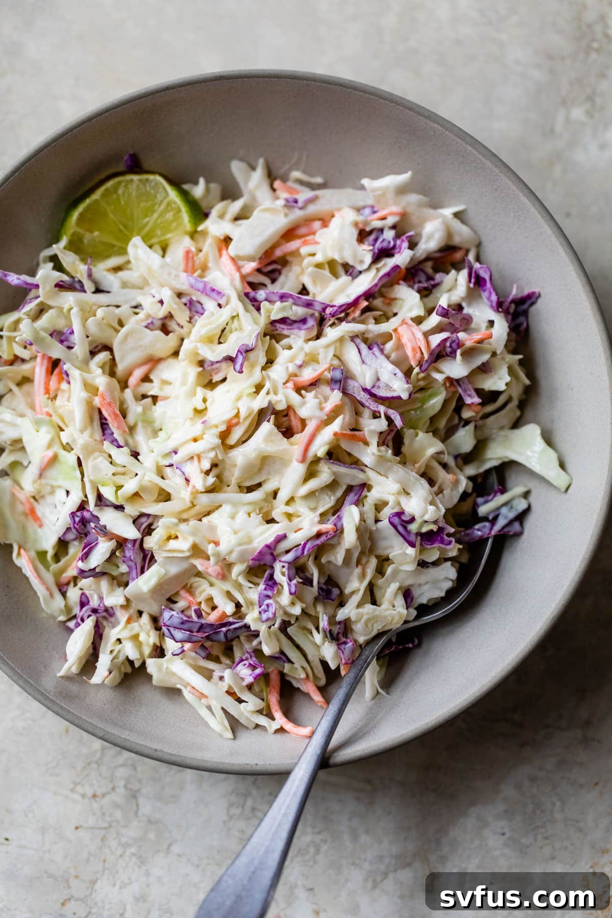 homemade coleslaw in a bowl with a fork, perfectly chilled and garnished
