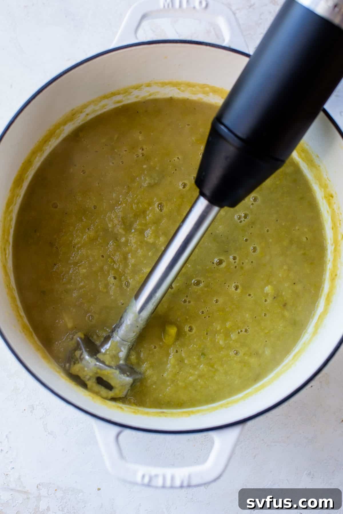 asparagus soup in a dutch oven pureed with an immersion blender