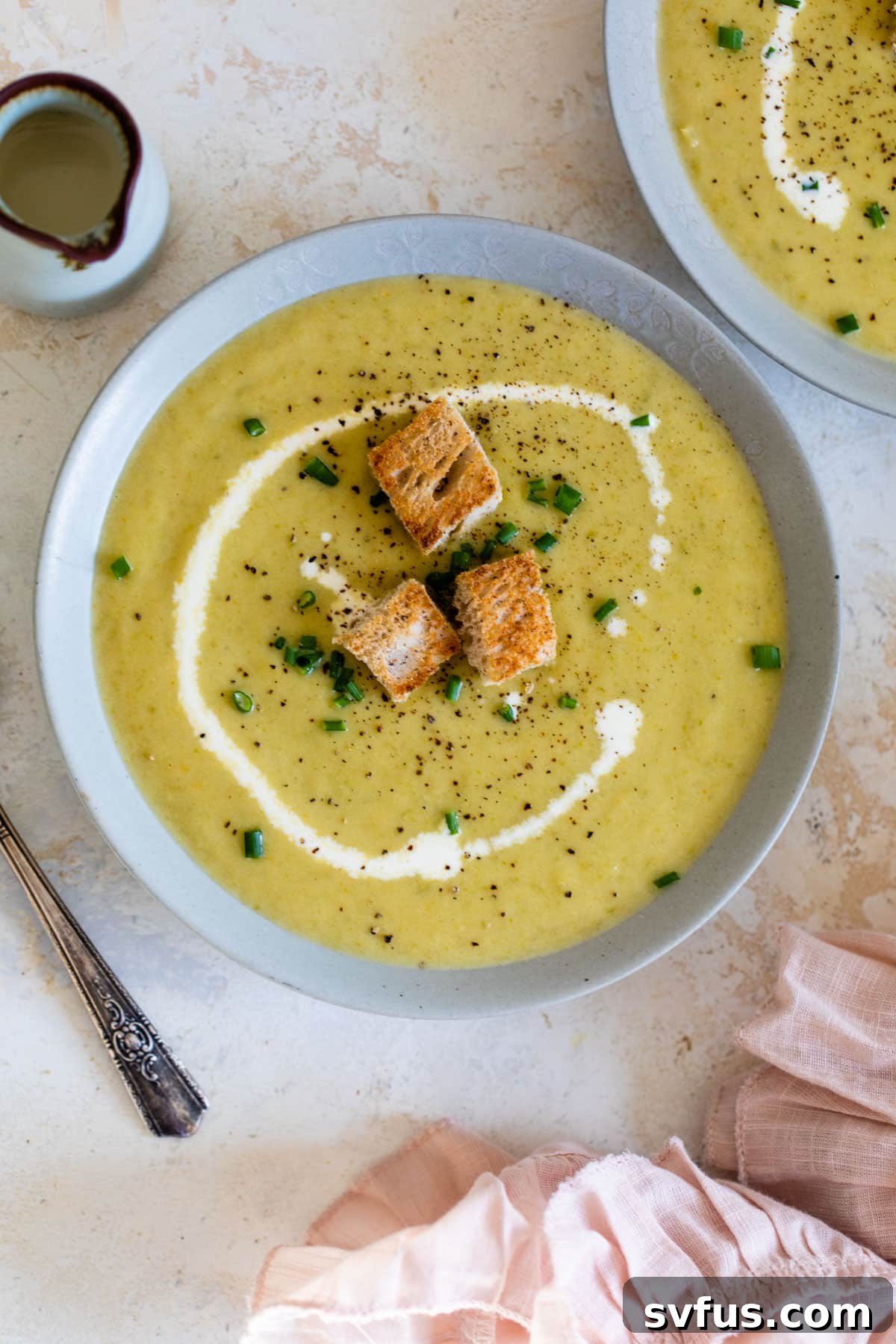 asparagus soup in a bowl topped with a swirl of heavy cream and croutons