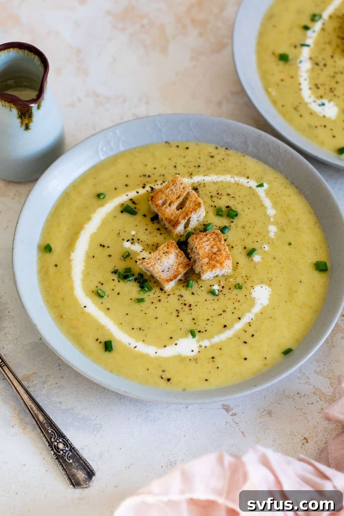asparagus soup in a bowl topped with a swirl of heavy cream and croutons