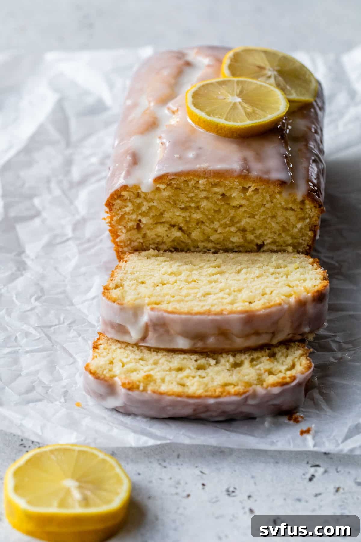 side view of lemon loaf with slices cut off and lemon slices on top