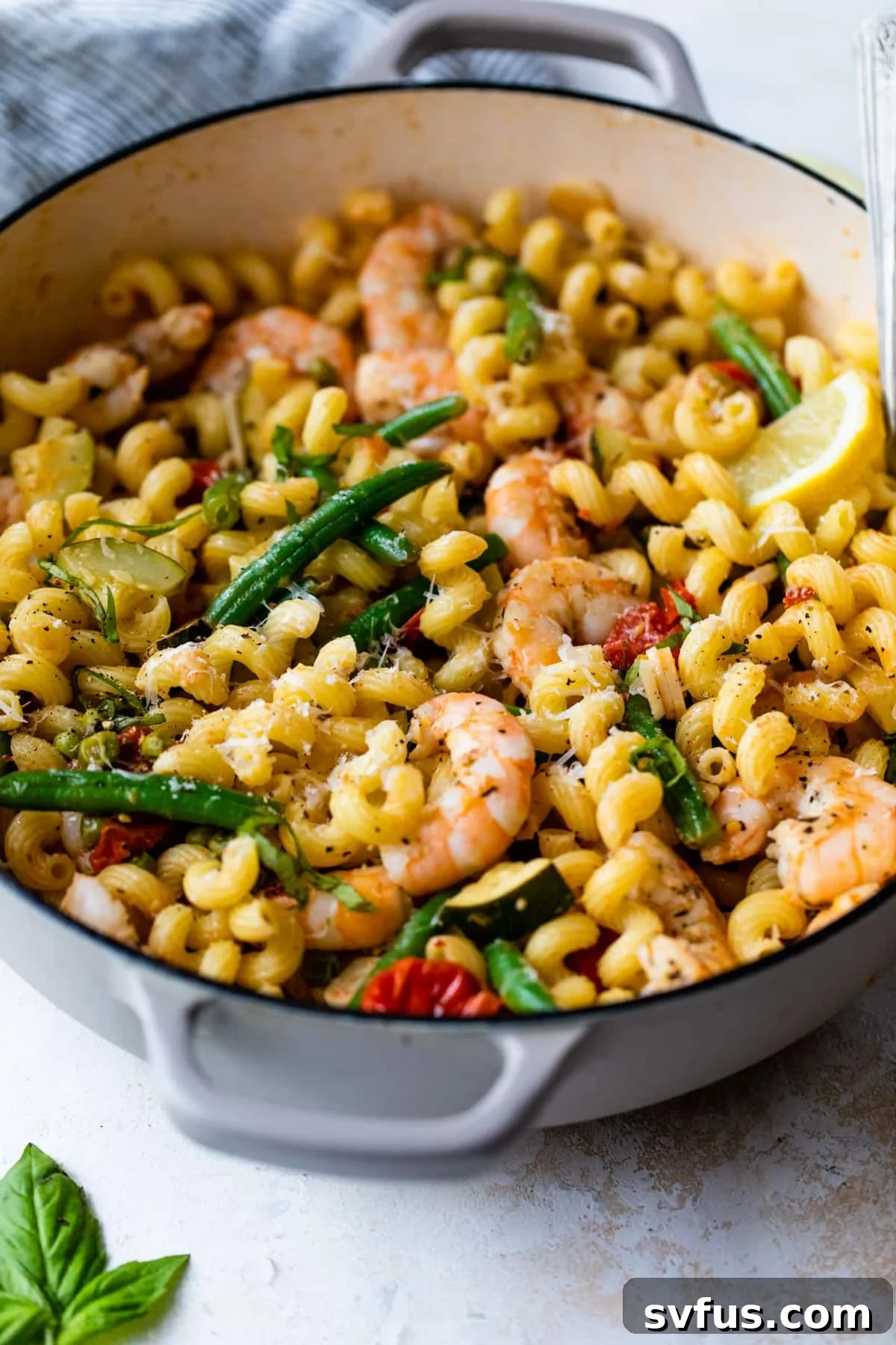 side view of shrimp primavera in a dutch oven with a spoon