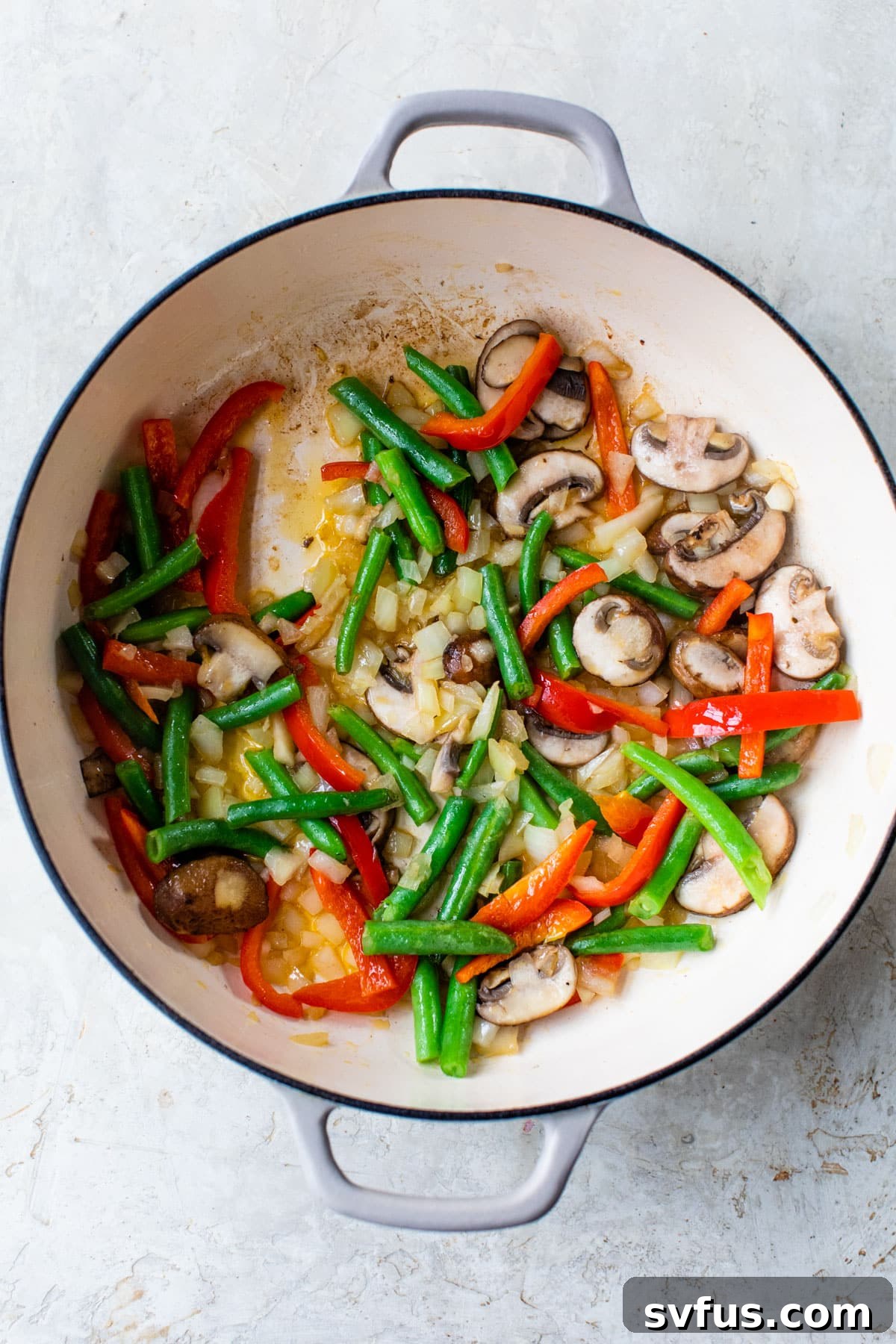 peppers, mushrooms, onion, and green beans sautéing in a dutch oven