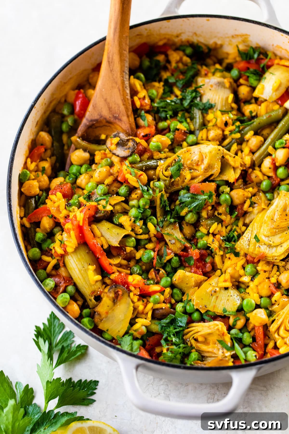 vegetable paella in a dutch oven with a wooden spoon