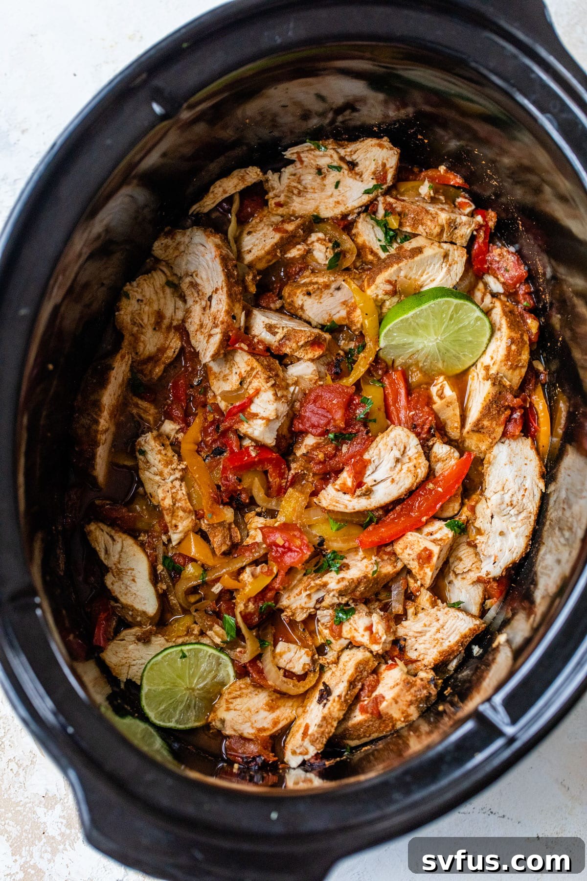 The finished slow cooker chicken fajita mixture inside of a slow cooker, ready for shredding and serving