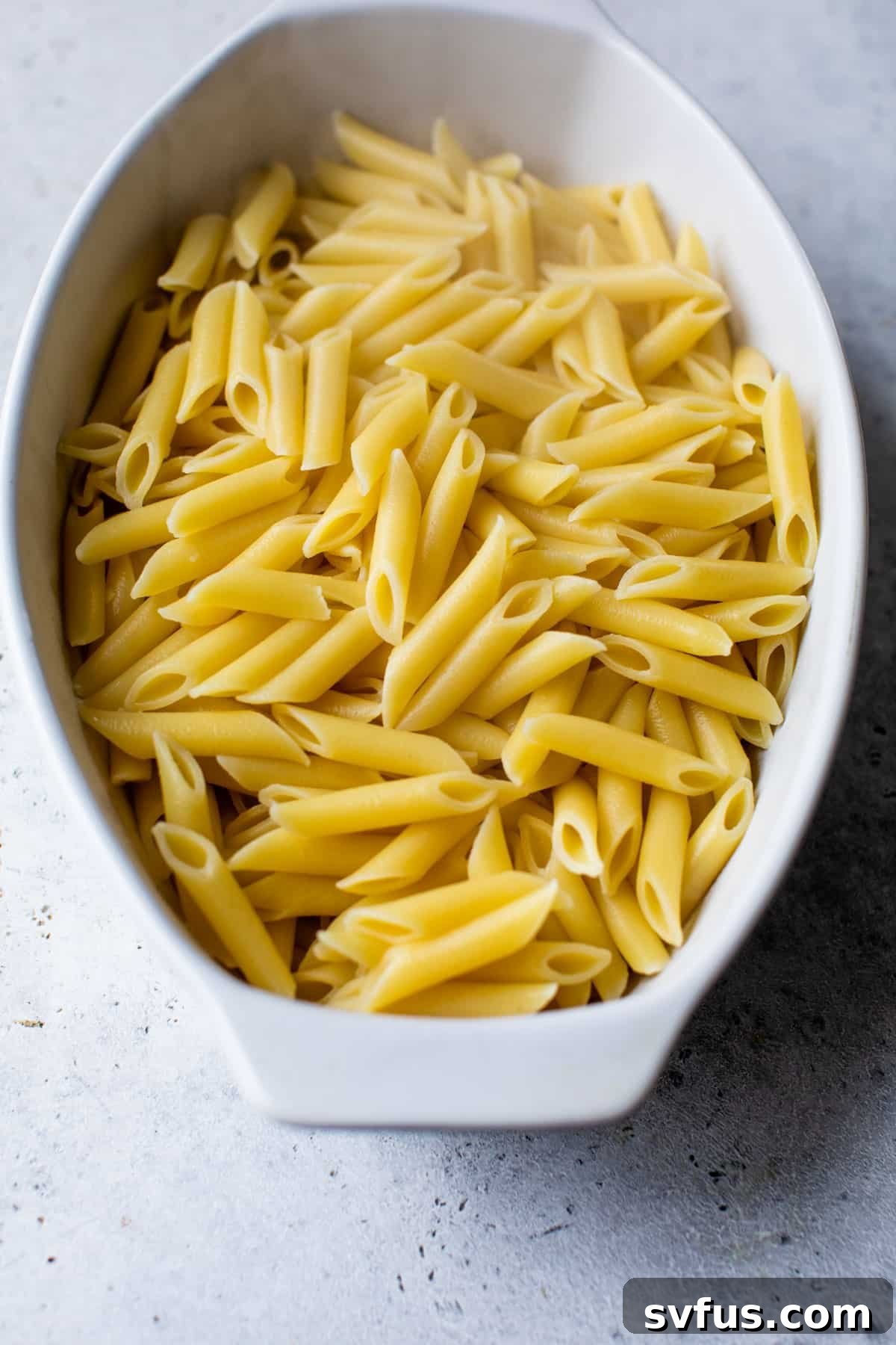 Cooked ziti pasta noodles evenly distributed in a casserole dish, ready for sauce.