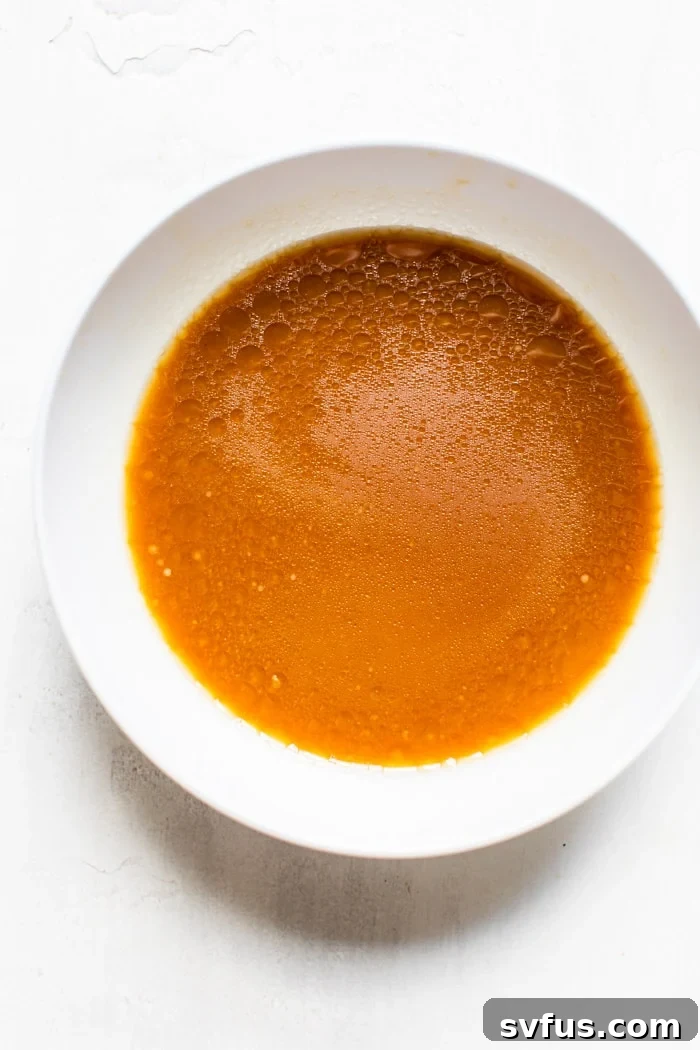 A small bowl containing a golden-brown Asian sauce, ready to be added to the chicken.