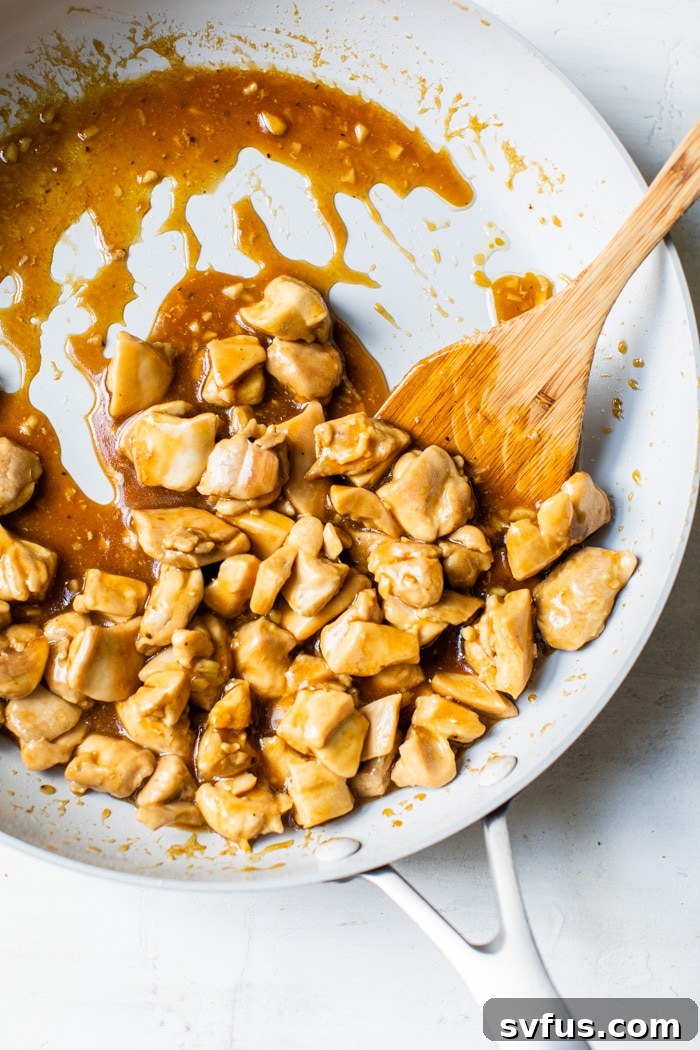 Cooked chicken coated in a rich, thick Asian sauce within a large skillet, ready for assembly.