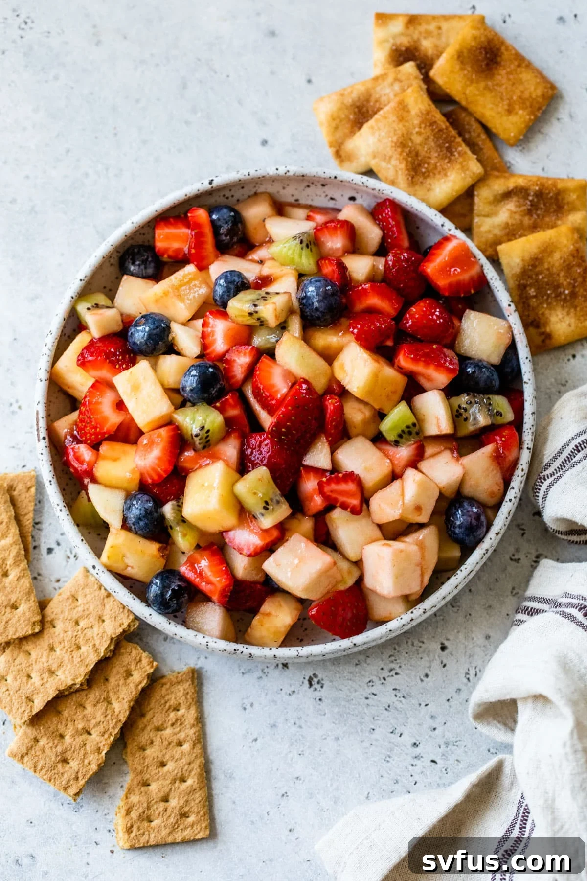 fruit salsa in a bowl with graham crackers and cinnamon pita chips off to the side