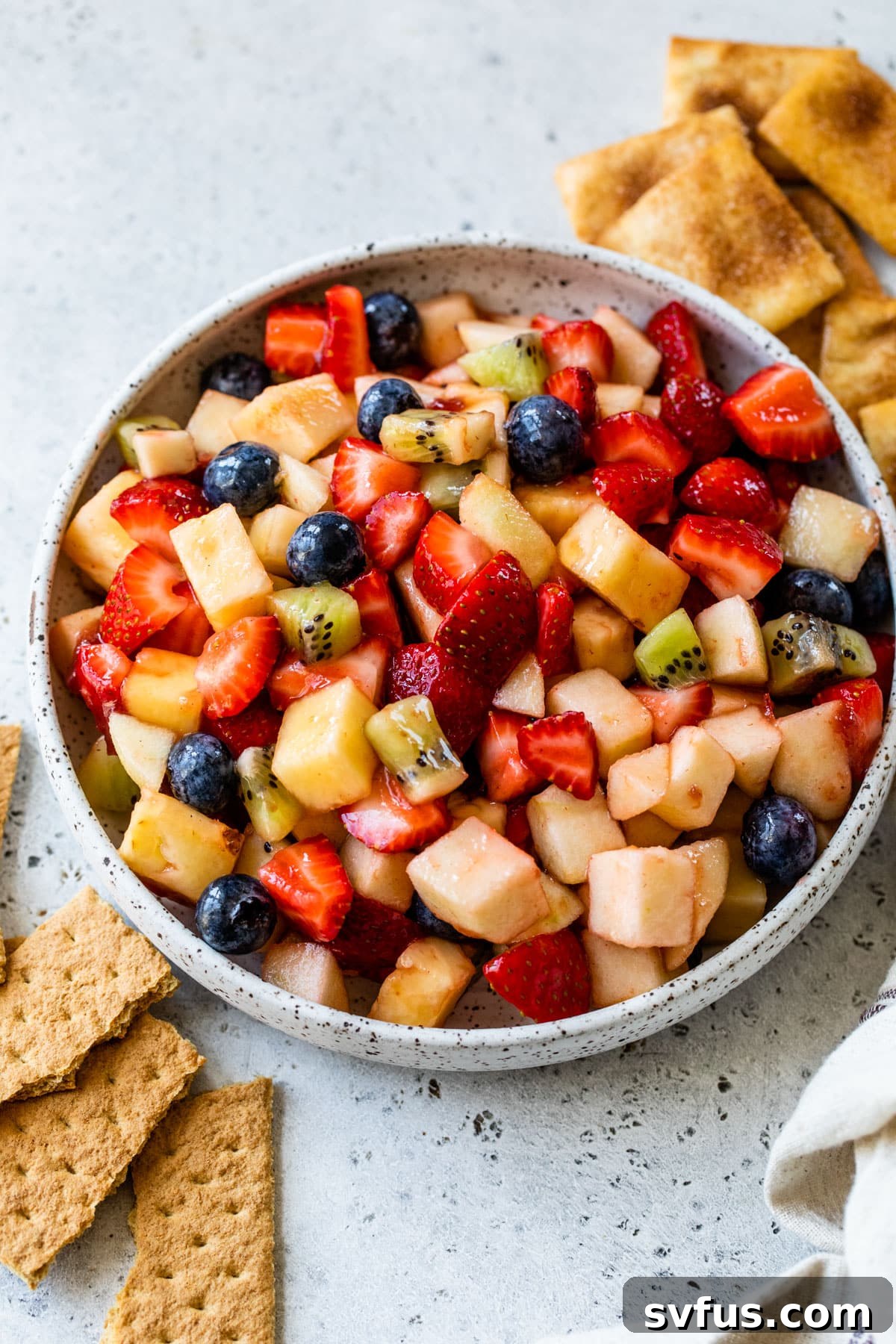 fruit salsa in a bowl with graham crackers and cinnamon pita chips off to the side