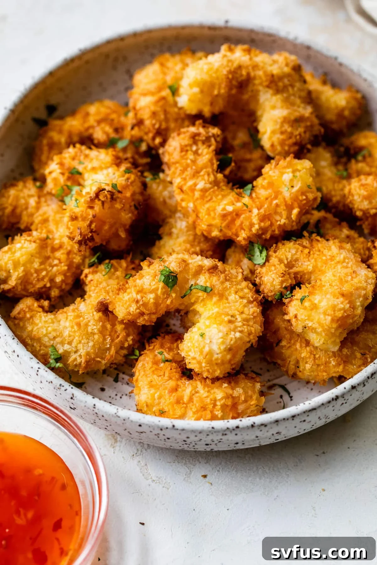 Air fryer coconut shrimp served on a plate with dipping sauce and lime wedges