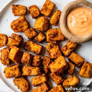 Air fryer tofu on a plate with dipping sauce on the side