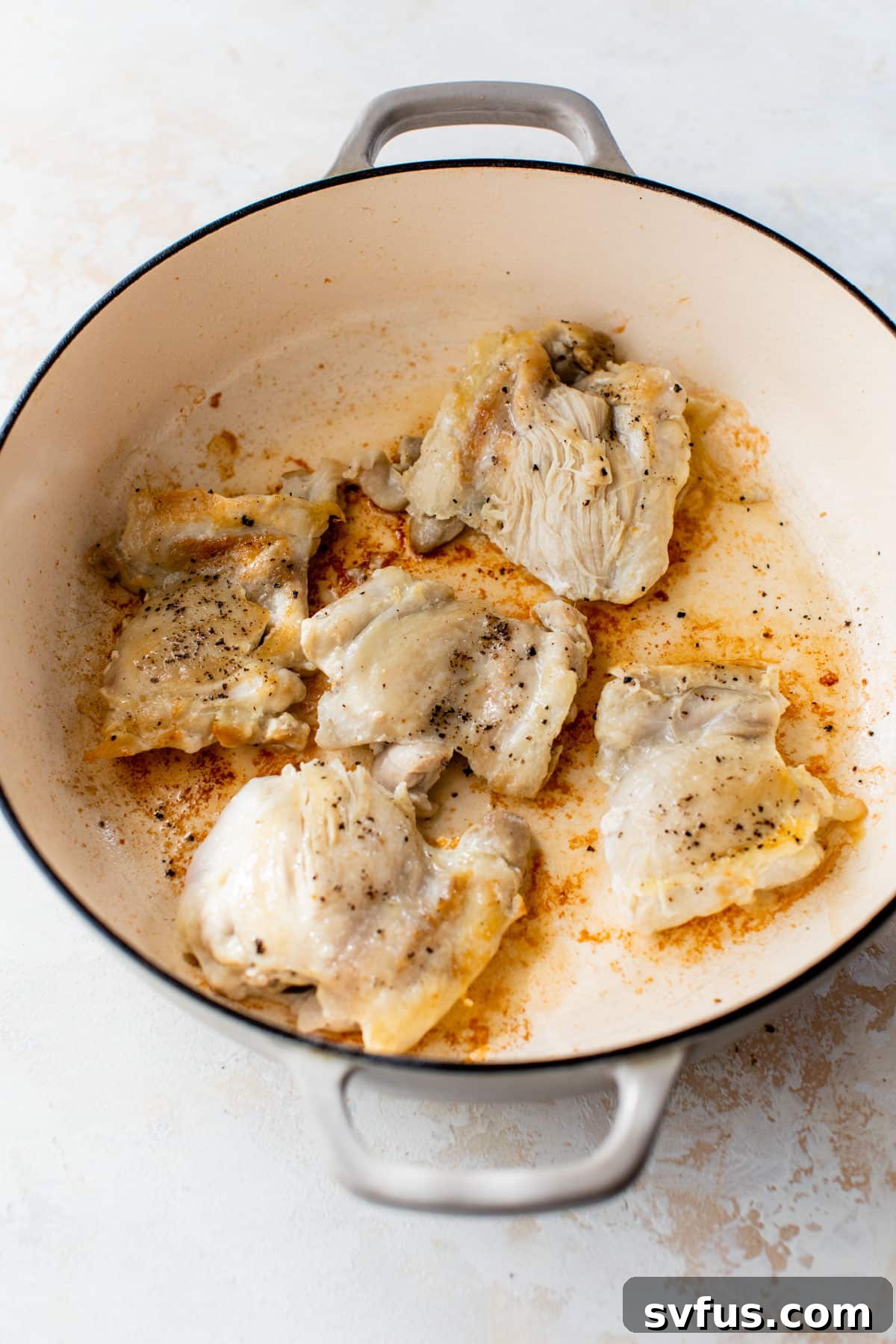 Chicken thighs searing to a golden brown in a Dutch oven, filling the kitchen with a delicious aroma.