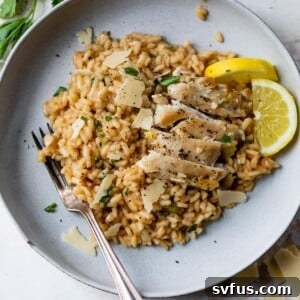 Chicken risotto on a plate with lemon slices and a fork