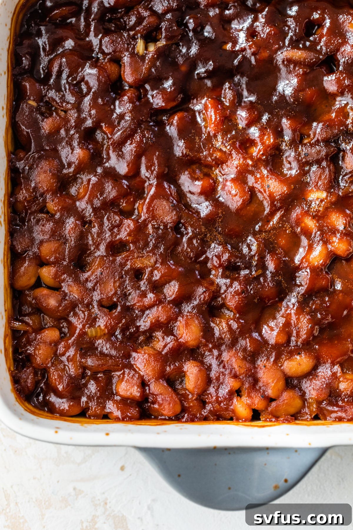 Vegan baked beans mixture in a baking dish, covered with foil, ready to go into the oven.