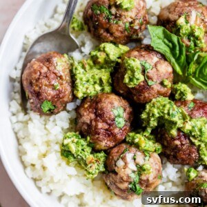 a bowl of cauliflower rice topped with meatballs and pesto
