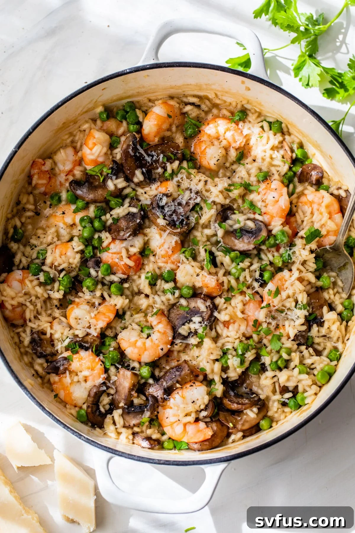 Finished shrimp risotto in a Dutch oven with a spoon, garnished with fresh parsley