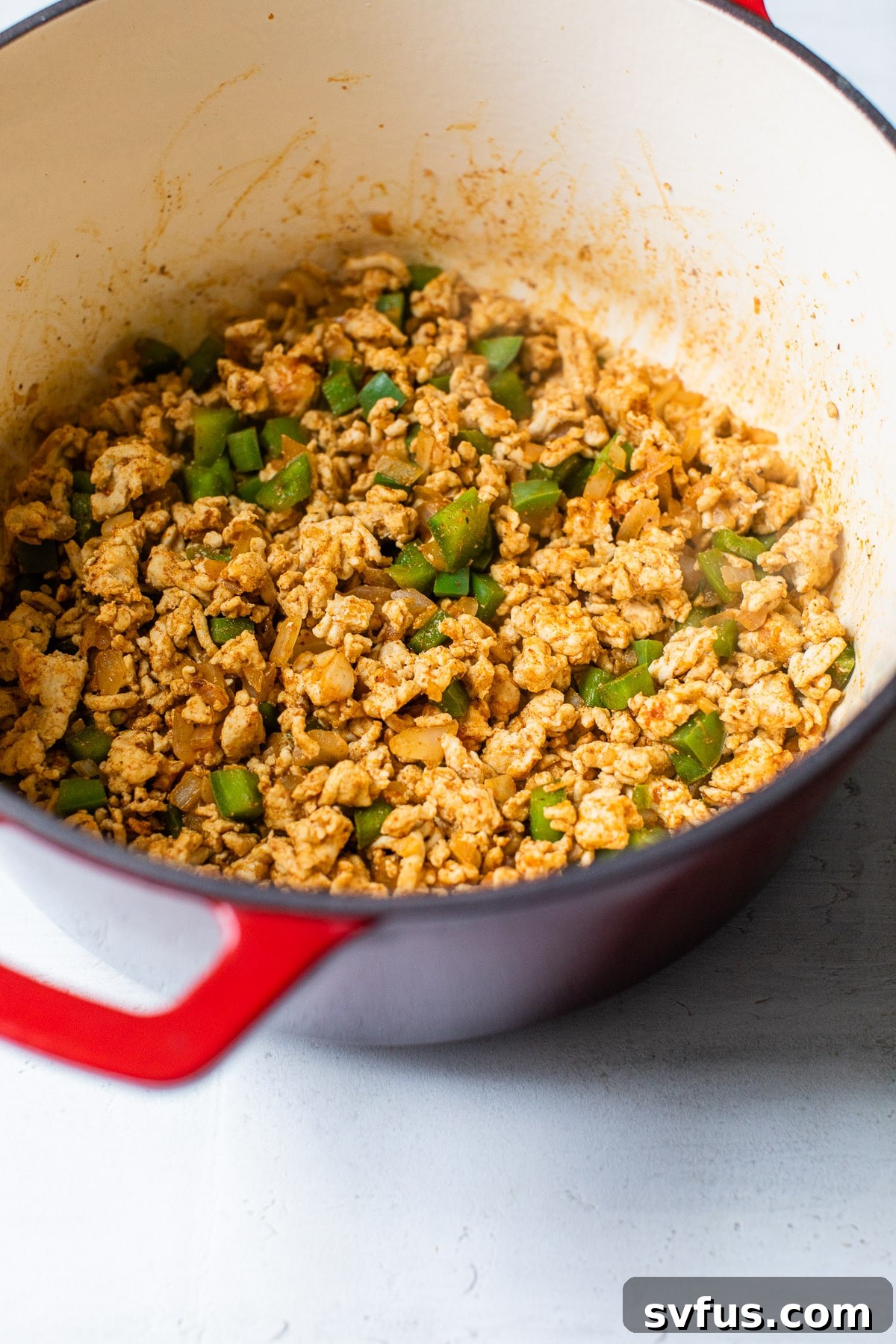 dutch oven with cooked ground turkey and diced green peppers