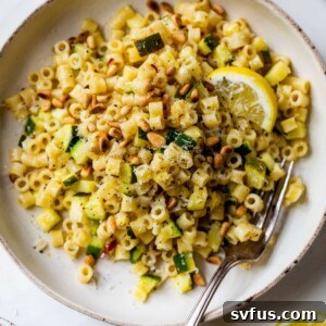 lemon zucchini pasta on a plate with a lemon slice and a fork