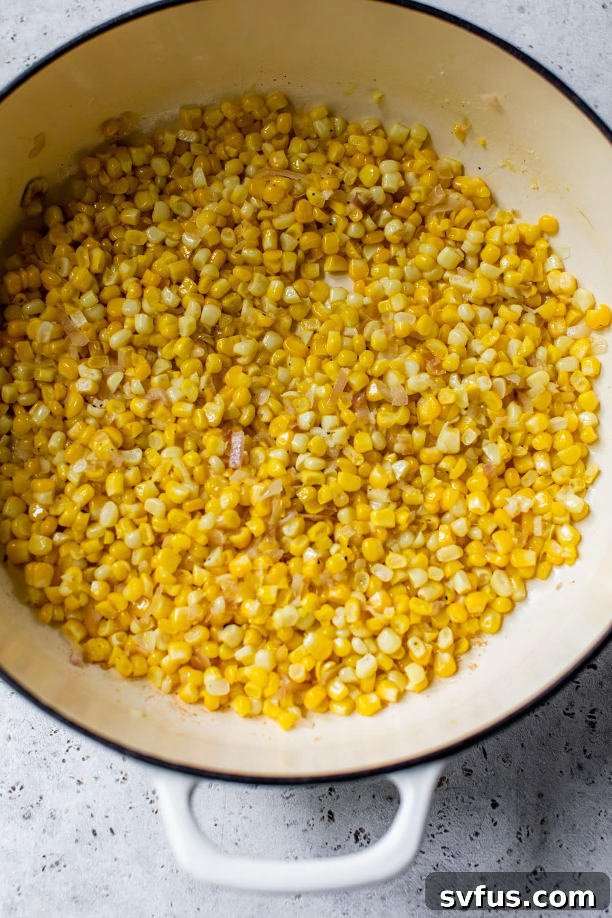 Fresh corn and shallot gently sautéing in a Dutch oven, releasing their sweet aromas.