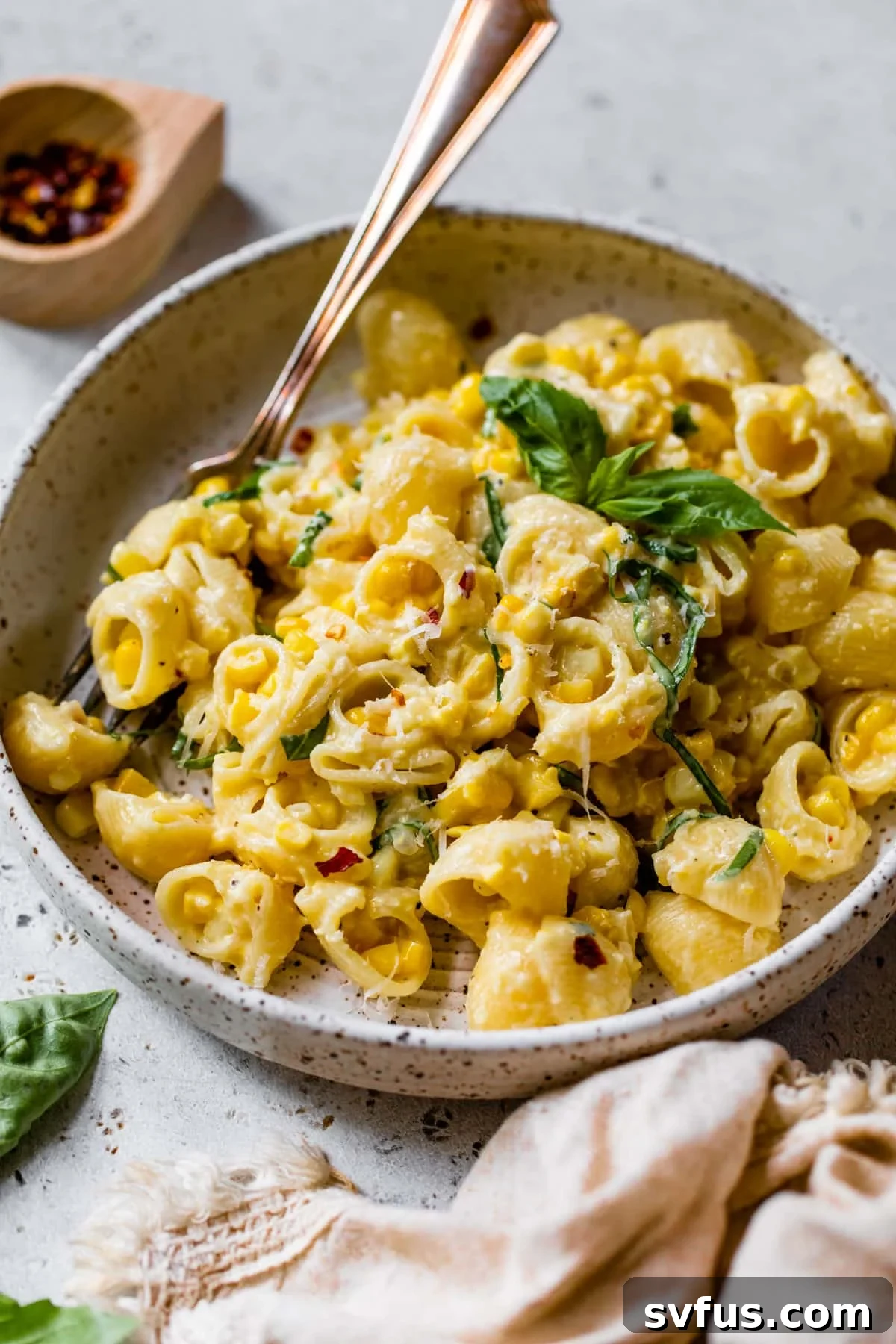A serving of creamy corn pasta in a bowl, garnished with fresh basil, ready for a delicious meal.