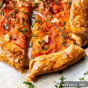 close-up of tomato galette with fresh thyme and chives on top and a slice cut out