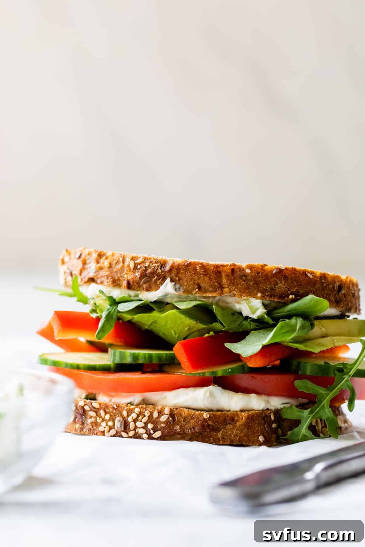 side view of a freshly made veggie sandwich on a wooden board