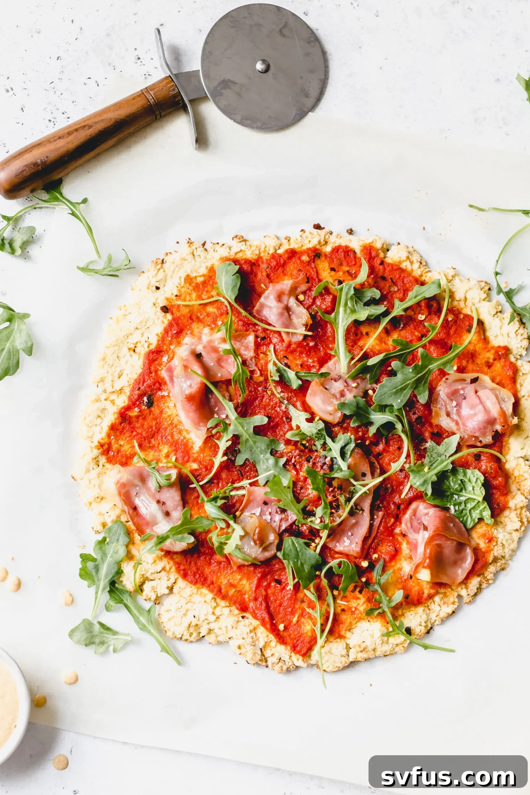 Close-up of a homemade Whole30 cauliflower crust pizza, showcasing its golden-brown texture and vibrant toppings.