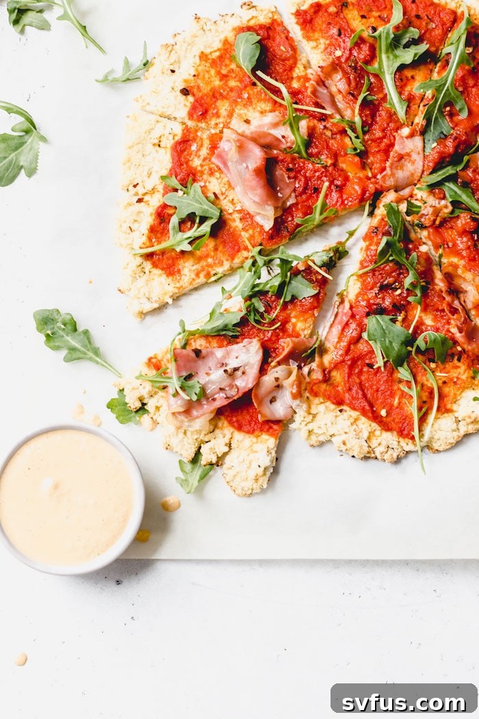 A slice of Whole30 pizza, showing the thin cauliflower crust and vibrant toppings, ready to be enjoyed.