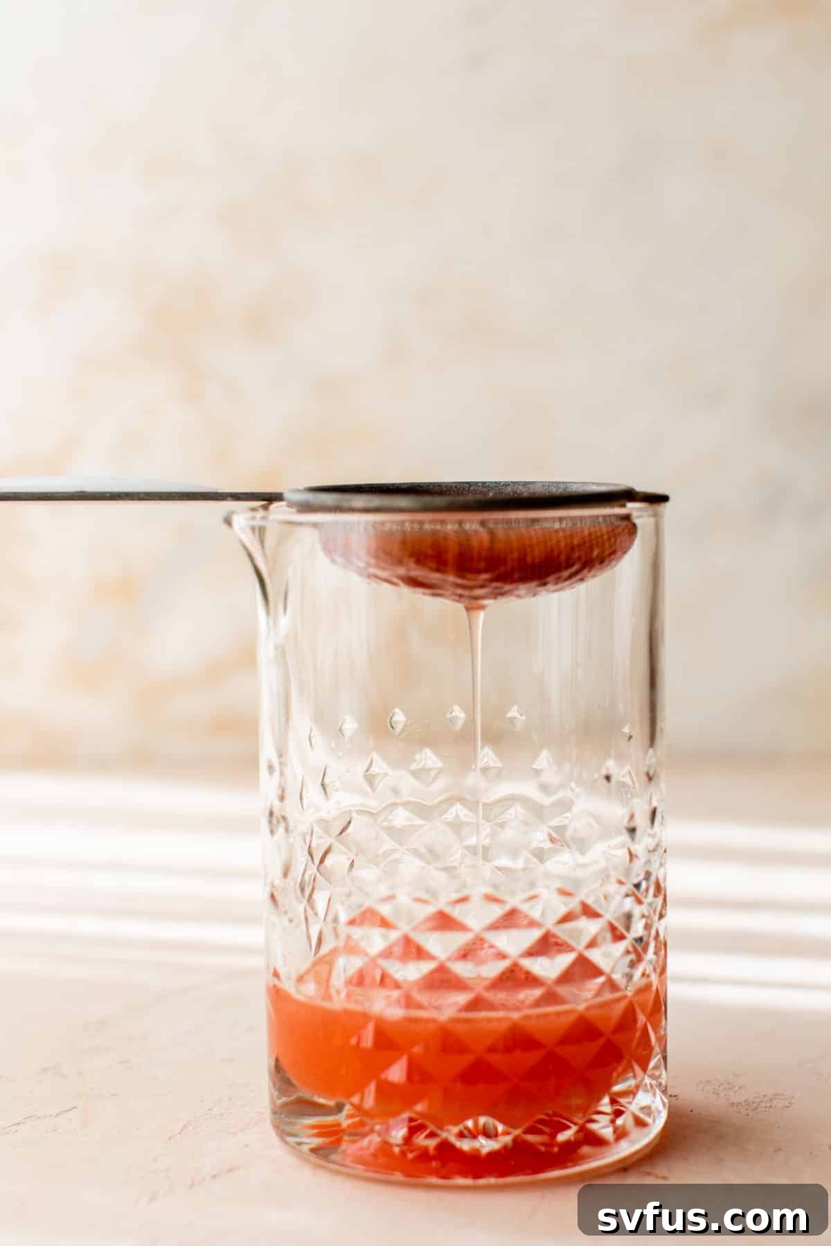 watermelon margarita being strained into a glass