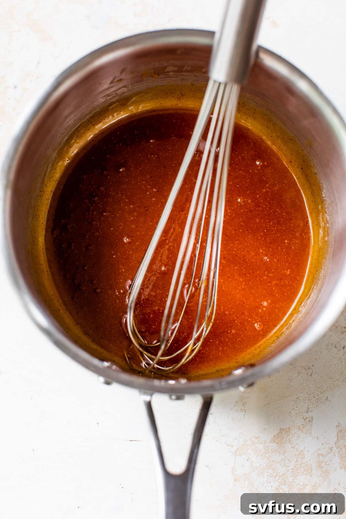 All hot honey sauce ingredients being whisked together in a small saucepan over heat.