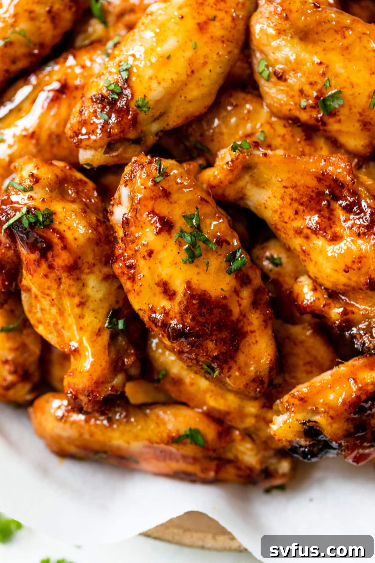 Close-up of freshly glazed hot honey chicken wings beautifully stacked on a serving plate.