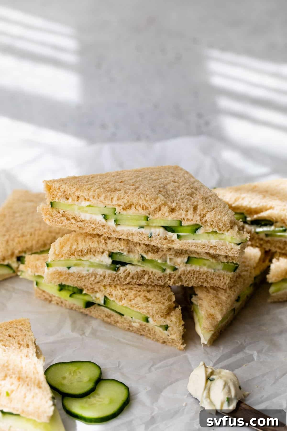 overview of a side view of cucumber and cream cheese sandwiches stacked on top of each other