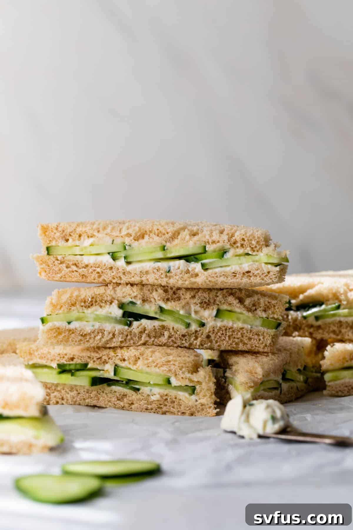 side view of cucumber and cream cheese sandwiches stacked on top of each other