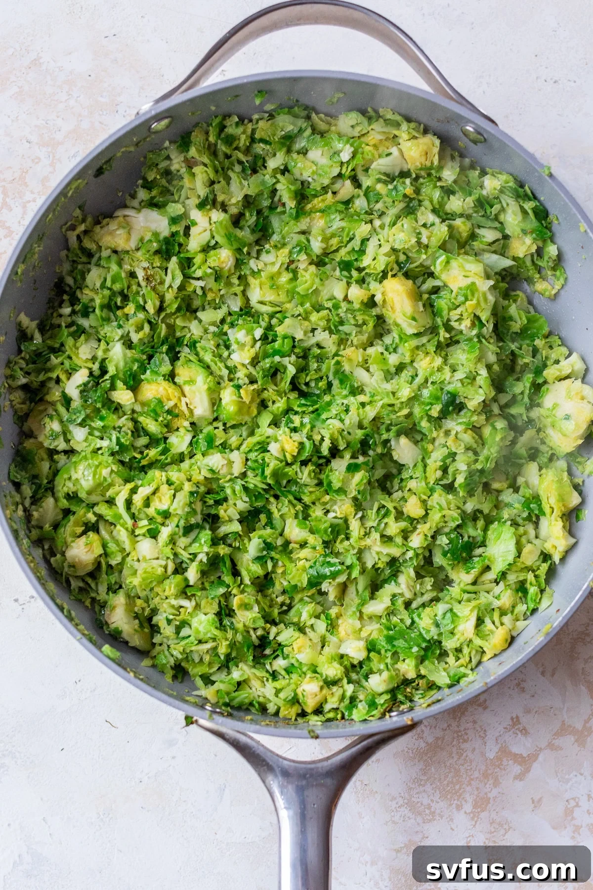 Shaved Brussels sprouts gently sautéing in a skillet, turning golden brown.