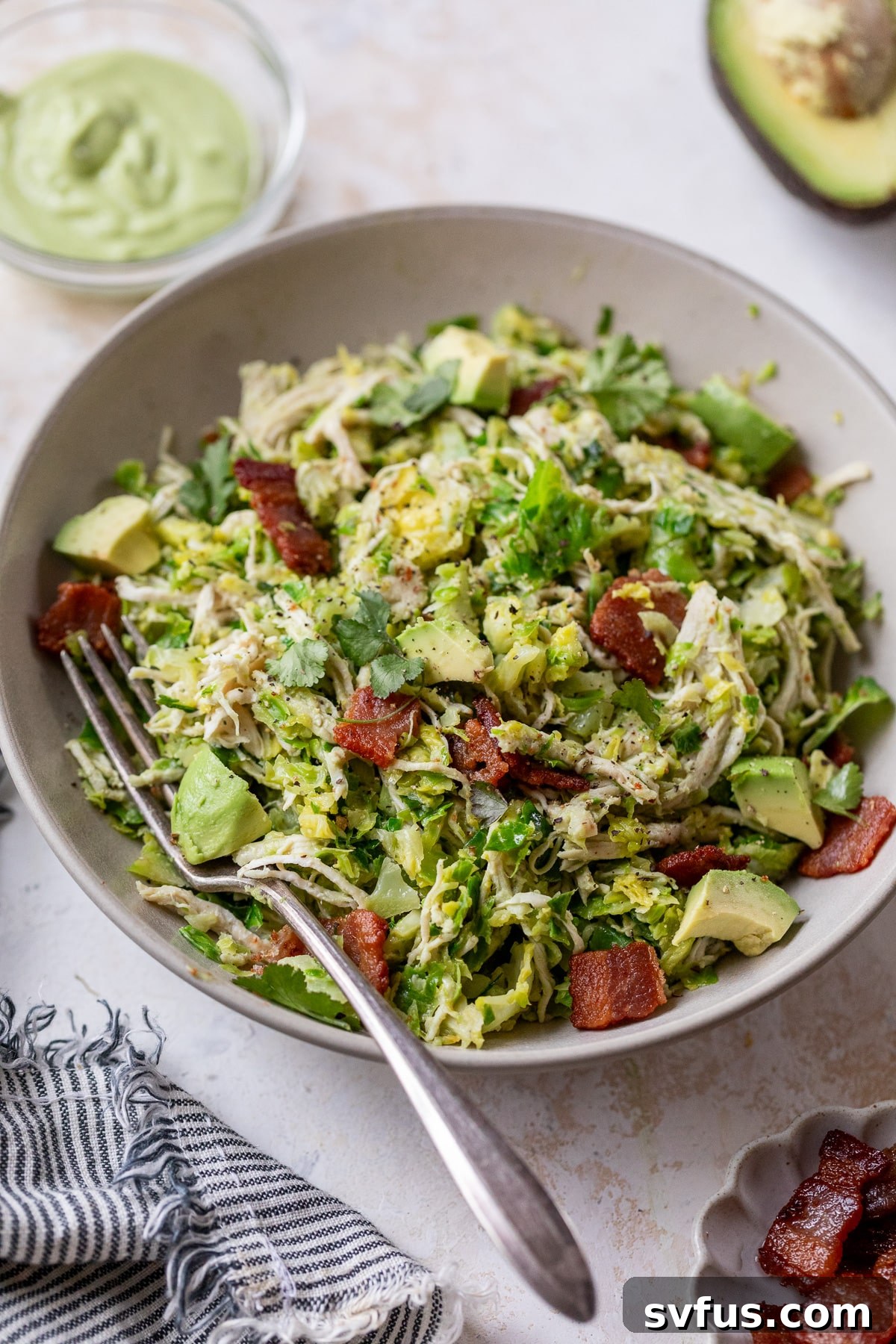 A bowl of Chicken Brussels Sprouts Salad with a fork, emphasizing its meal prep suitability.