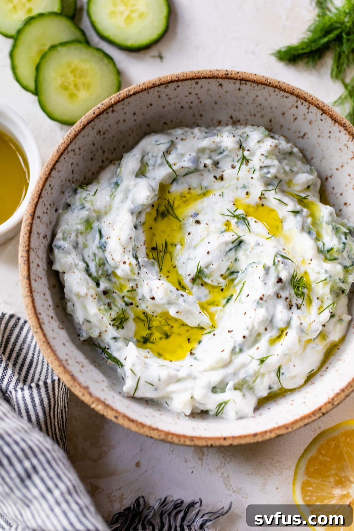 A close-up of a rustic bowl filled with homemade tzatziki sauce, adorned with a delicate swirl of olive oil, ready for serving or enjoyment.