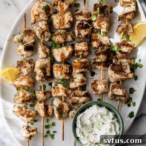 Greek chicken skewers on a plate with tzatziki sauce on the side