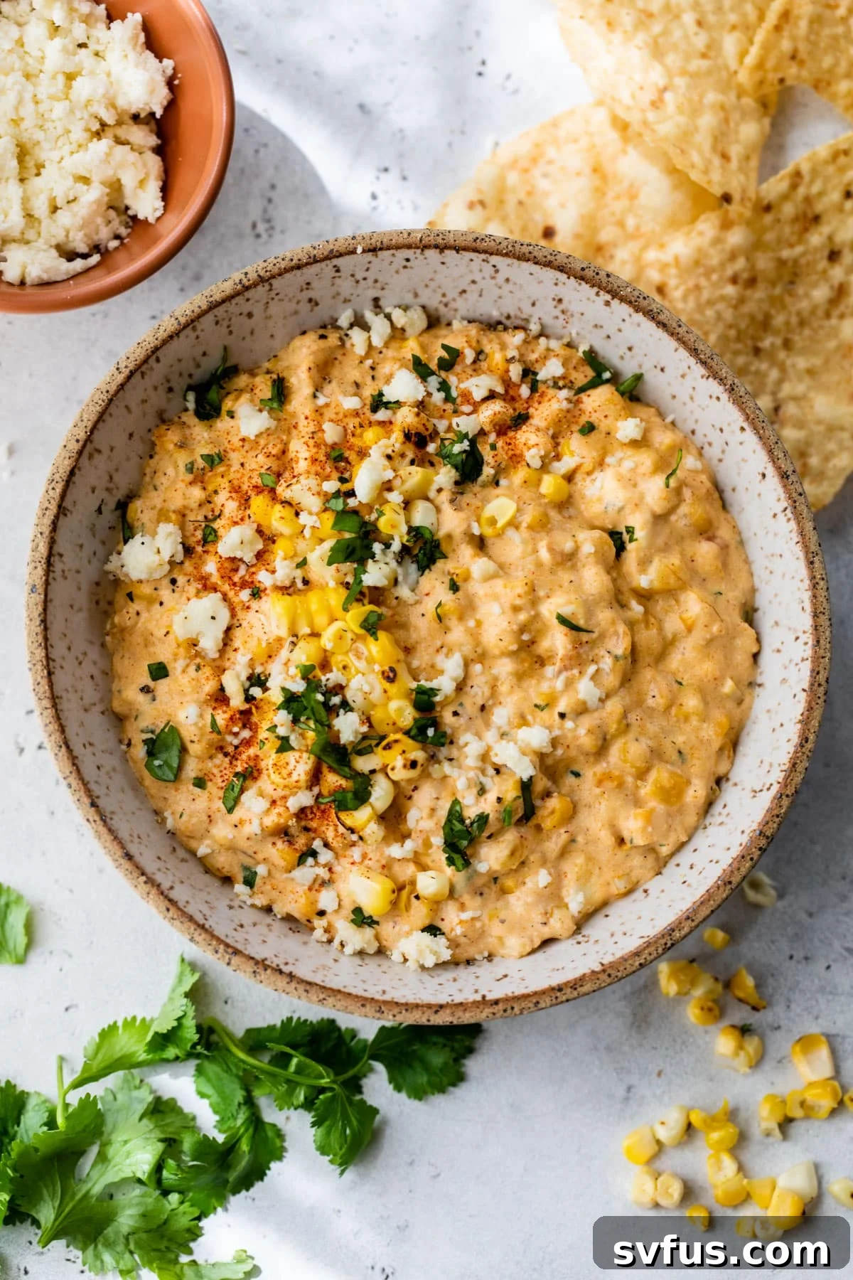 The finished corn dip, elegantly presented in a bowl, topped with fresh cilantro and crumbled cotija cheese.