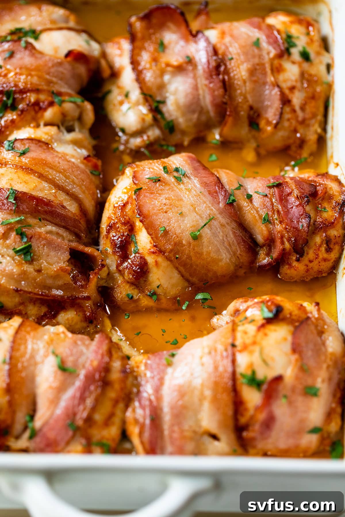close-up of cooked bacon wrapped around chicken thighs, golden and crispy in a baking dish